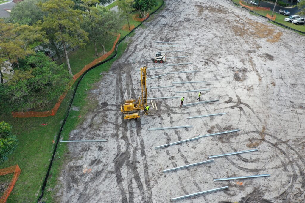 Aerial view of a crew driving steel piles for a ground-mount solar array